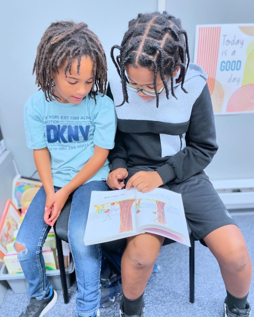 Two students at Delphi Academy Boston collaboratively reading and engaging with a picture book, demonstrating peer learning in action